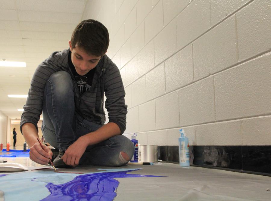 Jacob Graziani (10) paints a shark on a banner to hang on the hallway wall. The Sophomores went with a “Jaws” theme as a twist on the Homecoming theme “Under the Sea.”