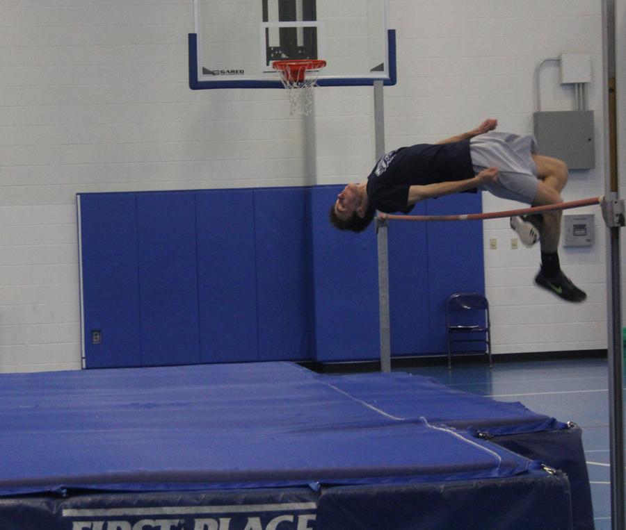 Kyle Crawford (12) practices the high jump. After he lands his team mates clap and compliments him.