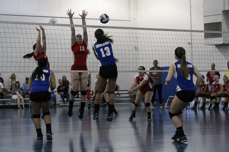 Anna Mihajilovic (9) hits the ball over the net while her opponent attempts to block her hit. Mihajilovic successfully spiked the ball and scored.