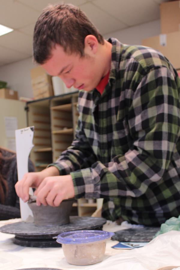 Logan Sommer (10) adds a coil to the top of his pot. He smoothed it out with his hands and continued to add coils until he gets the shape he wanted.
