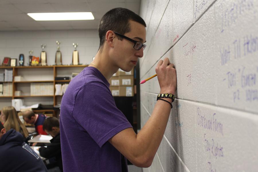 Theofanis Rauch (12) writes the title of the most current book he read on the back wall of Mrs. Kathryn Clark’s classroom.  Rauch sat in the back of the classroom, closest to what has been deemed the “reading wall.”