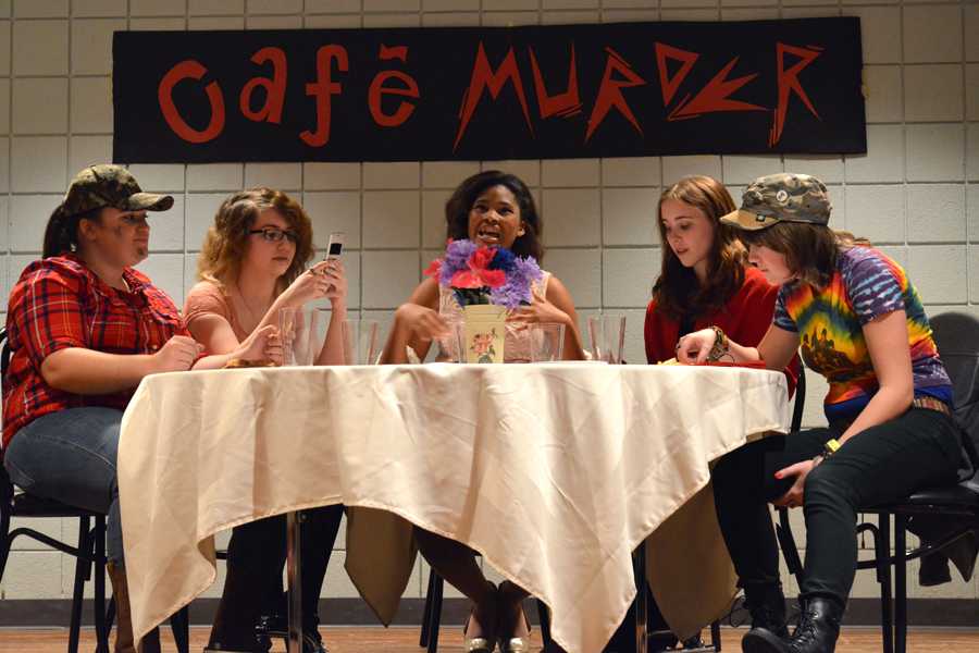Five cast members of Cafe Murder sit around the dinner table.  The performance revealed that in the end, Rosemary, played by Kendra Williams (11), center, was said to have been murdered.  
