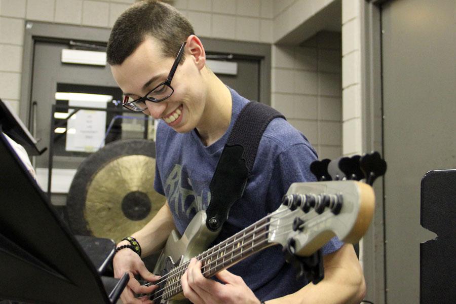 Theofanis Rauch (12) smiles while playing the bass along with the rest of the band. In winter percussion, there is modern rock four-piece (drums, guitar and bass) that plays along with the other instruments. 