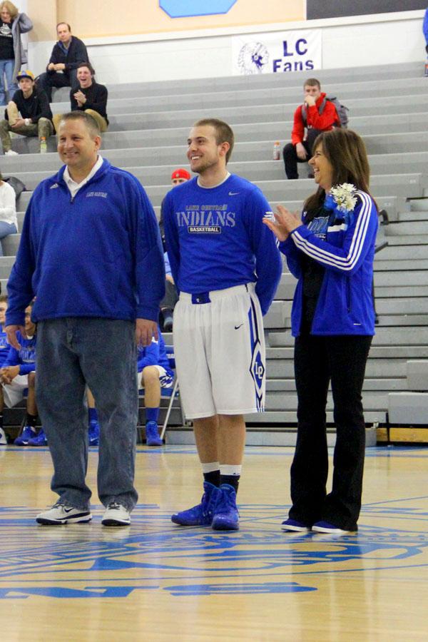 Matthew Meneghetti (12) and his parents laugh as they walk  across the court for his Senior Night. This was his last home game and was against Michigan City, with a score of 70-52 LC.