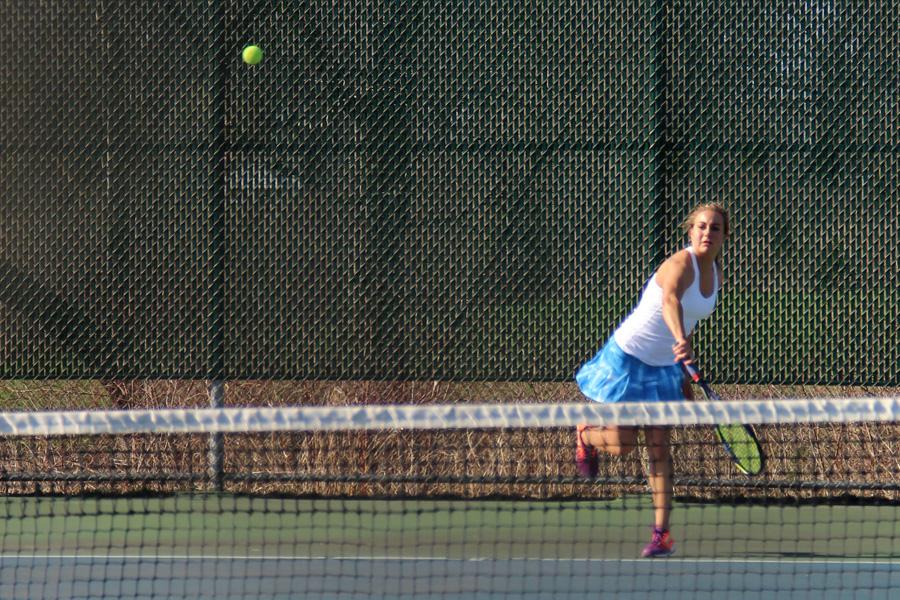 Jory Swider (12) serves the ball in a singles match. Swider won the match, helping the team win overall.