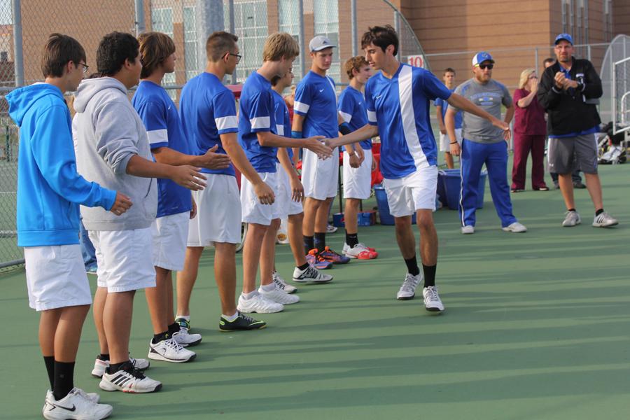 Richard Larson (10) high-fives his teammates after being introduced. Larson played number three varsity singles. 