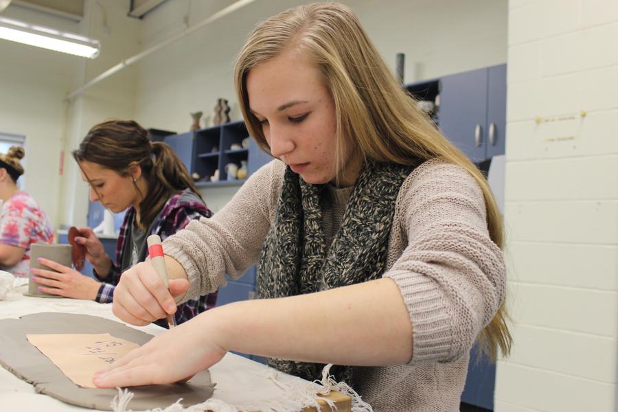 Hannah Studer (11) uses a fettling knife to cut out the base of her mug. She previously rolled the clay out in an even slab. 