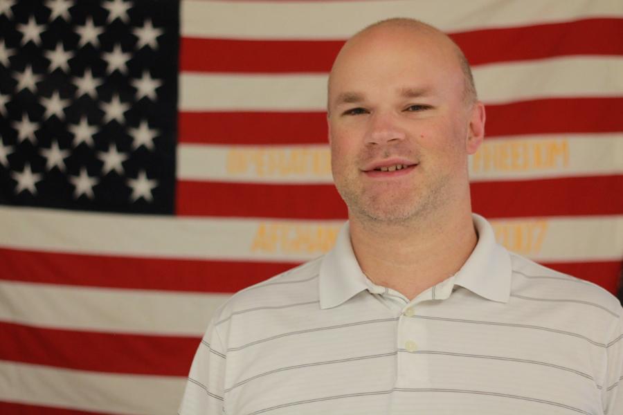 Mr. Joseph Bafia, Social Studies, poses in front of an American flag.  Starting last year, Mr. Bafia’s students participated in sending holiday cards to soldiers overseas.