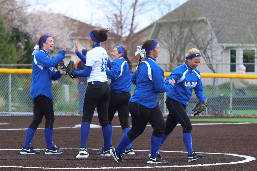 The girls on the field high-five each other on the mound after a good pitch by Annabel Karberg (12). During game, after each accomplishment, the ladies encouraged each other.