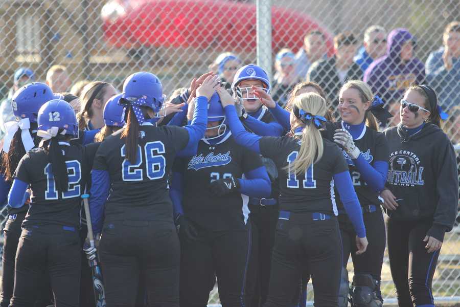 The varsity softball team celebrates a home run from Julia Schassburger (11). Schassburger, the starting pitcher, helped her team by scoring three runs in a single at bat.