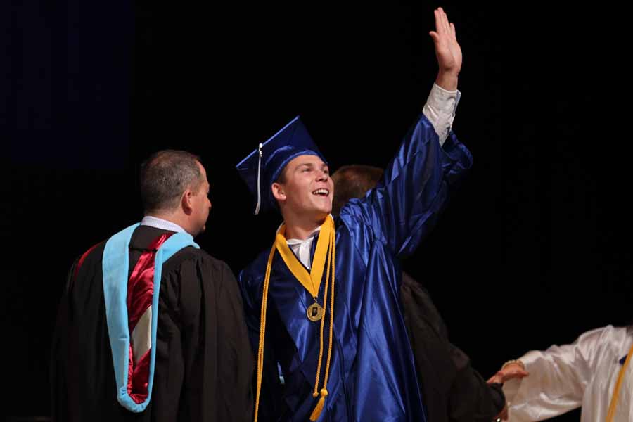 Logan Lambert (‘15)  waves to his family while walking across the stage. The Star Plaza was filled with friends and family of the senior class.  