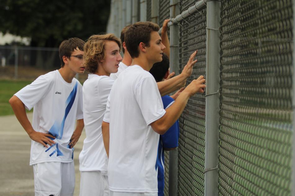The boy’s tennis team watches the last match finish. The boys won 5-0. 