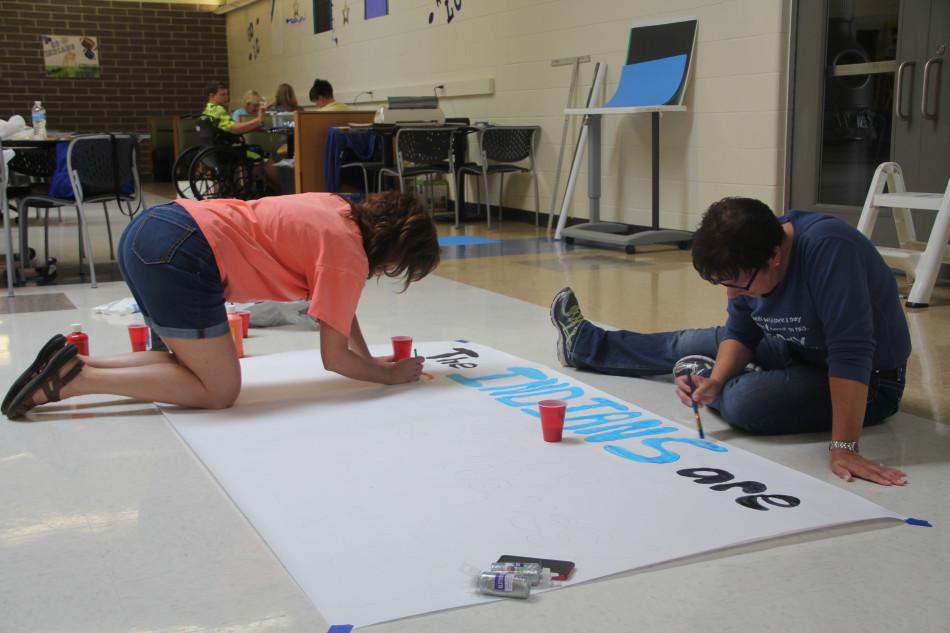 The Gridiron Moms paint a banner in the cafeteria. “Good luck. Sack the Wolfpack,”   Nicole Kelly, member of the Gridiron Moms, said.  The Gridiron Moms hope for the best for the upcoming game this Friday.