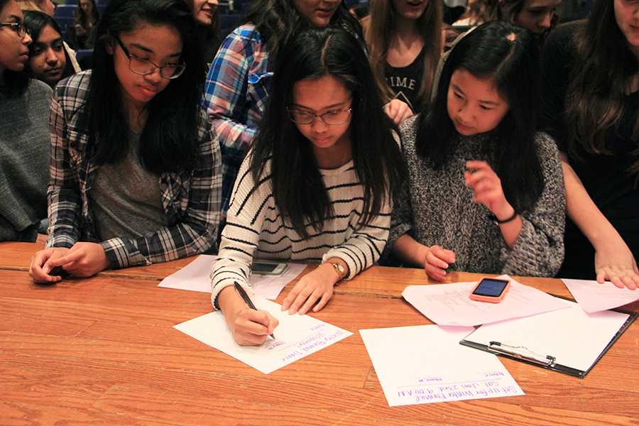 Kelani Benson (10), Melicah Rodriguez (10) and Ruth Chen (11) sign up to set up for Winter Formal. They were at the meeting in the LGI.