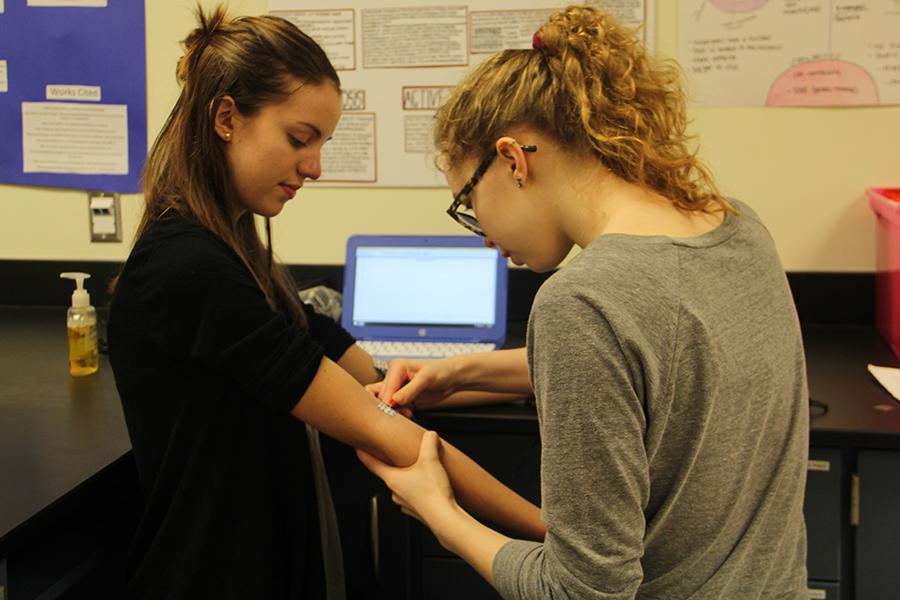 Katlyn Ardnt (11) attaches an electrode sticker on Michelle Buckmans  (11) arm.  The Science Club members used Purdue Univerisity’s laptops for monitoring heart rate.  
