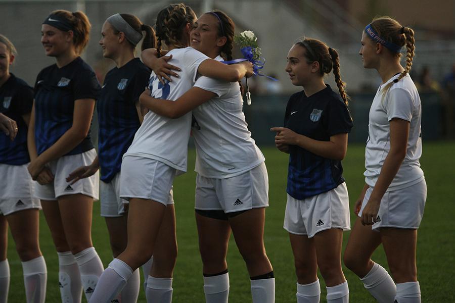 Meghan Teumer (12) hugs teammate while walking out for Senior Night. Teumer’s teammates gave hugs to all the seniors when the walked out. 
