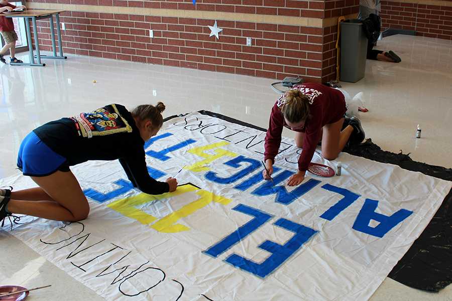 Sofia Hay (12) and Darby McGratch (12) work on the banner for senior class cabinet. The banner was hung on a wall in Main Street