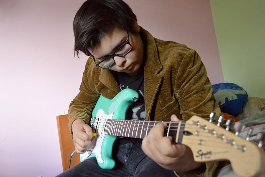 Matthew Mergenthaler (10) plays the guitar in his room.  He emphasized the importance of his bedroom as the source of his music and its distinct, lo-fi quality. 