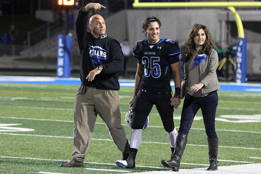 Nicholas Lucas (12) walks down the field as his dad points toward him while the fan section chants his last name. Lucas was escorted by his parents during the senior night portion of the game which took place on Oct. 14.