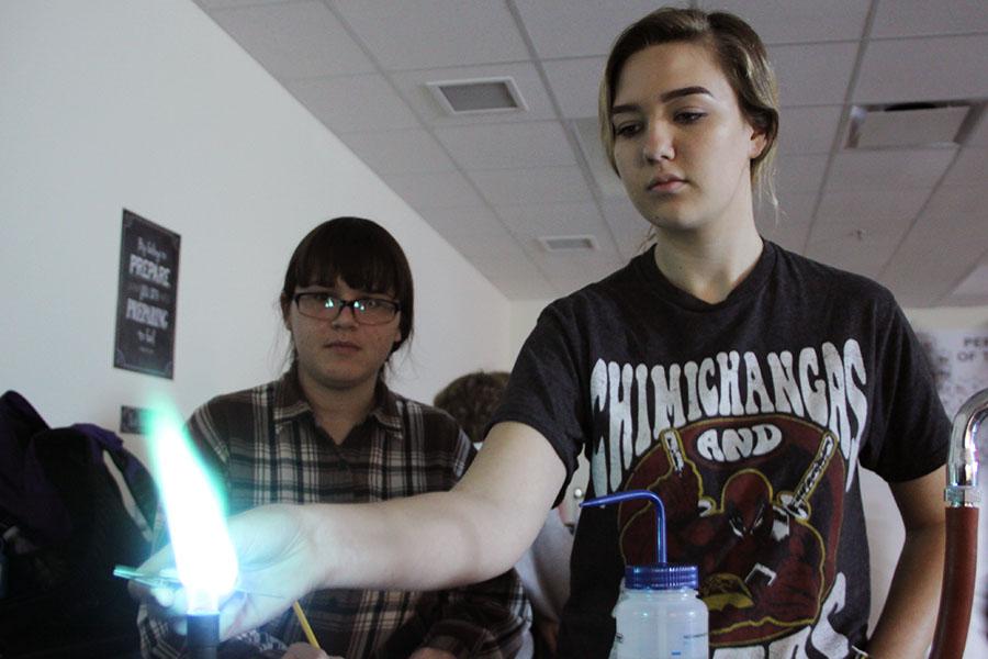 Kaylyn Lee (10) and Allison Magura (10) observe the flame to identify what chemical was being burned. Chemicals that burned blue had a high energy.
