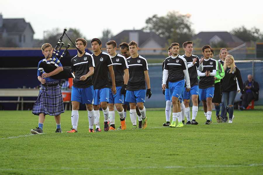 Varsity boys soccer seniors walk out onto the field with Trent Schneider (9), who is playing the bagpipes. It was Senior Night for the Indians. 
