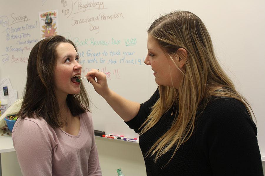Olivia LaVoie (10) gets her tongue painted green by Madison Frederick (11) on Sensation Day in AP Psychology class. LaVoie turned out to be a supertaster.  
