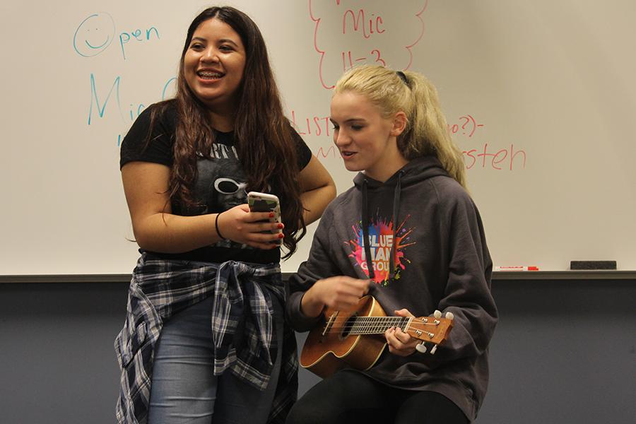 Jocelyn Hansen (9) holds up lyrics for Ava Solis (9) who sings “Spirits” by The Strumbellas. Hansen held up lyrics for multiple people throughout this Open Mic meeting. 
