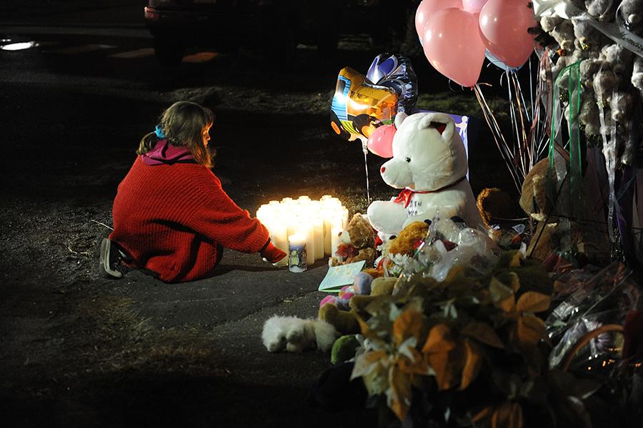 A girl lights candles at a memorial near Sandy Hook Elementary School on Saturday, December 15, 2012 in Newtown, Connecticut, a day after a shooting rampage at the school. (Olivier Douliery/Abaca Press/MCT)