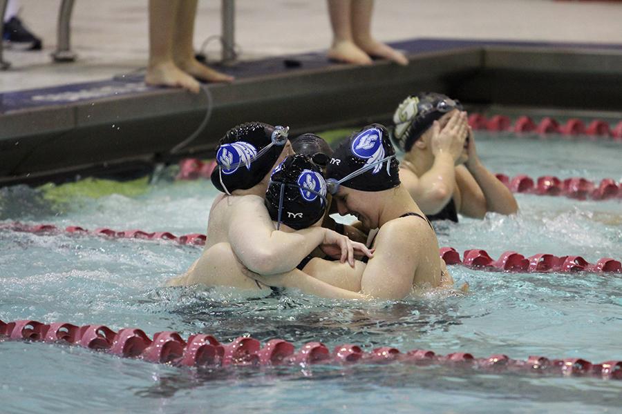 Savanna Spears (11), Maggie DePirro (9), Rachel Albright (11) and Sara Erwin (12) hug after earning third in the 200-yard freestyle relay. This relay event helped the team accumulate points.

