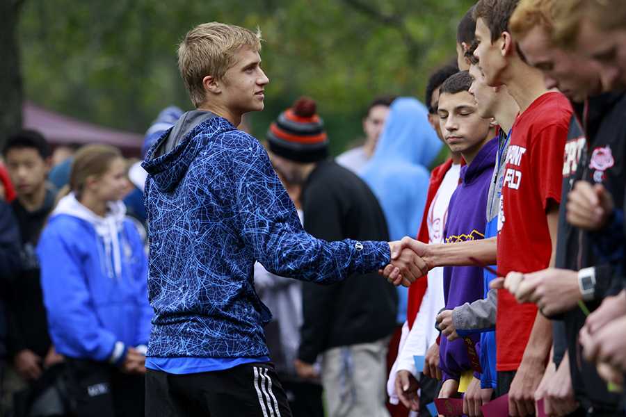Mitchell Polaski (11) shakes the hand of a runner at the cross country Regionals meet. Polaski has been on the varsity teams of cross country and track since freshman year. Photo by: Ruth Chen (12)