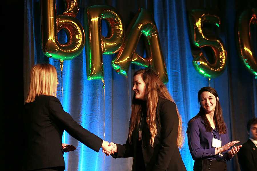 Courtney Carlson (11) smiles as her sister Kayla Carlson (10) shakes a BPA District President’s hand after placing tenth in open event Management, Marketing and Human Resource Concepts. Courtney Carlson (11) placed fifth in the same event.