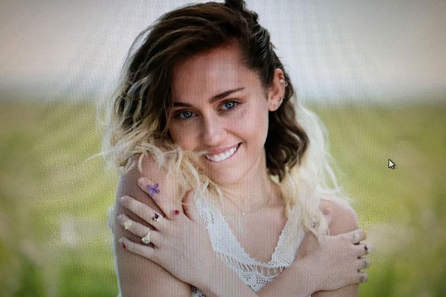 Miley+Cyrus+sits+in+the+grass+along+the+beach+smiling.+Cyrus+released+her+single+on+May+11.