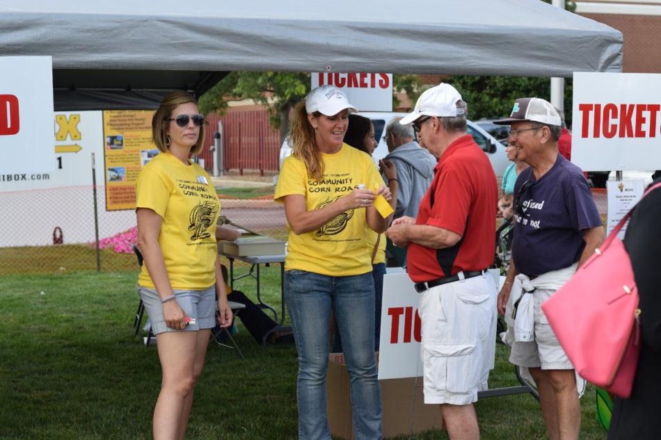 A woman gives a food ticket to a member of the community. There are multiple corn roasts held around the Region over the summer.