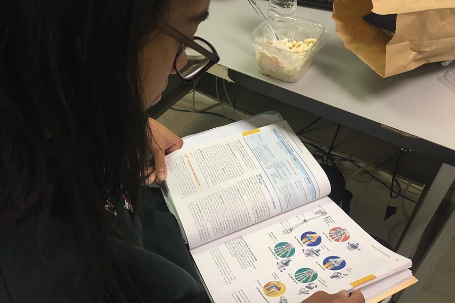 Kelani Benson (12) studies her anatomy book while eating lunch. Students have gone to the library during lunches to study for finals.