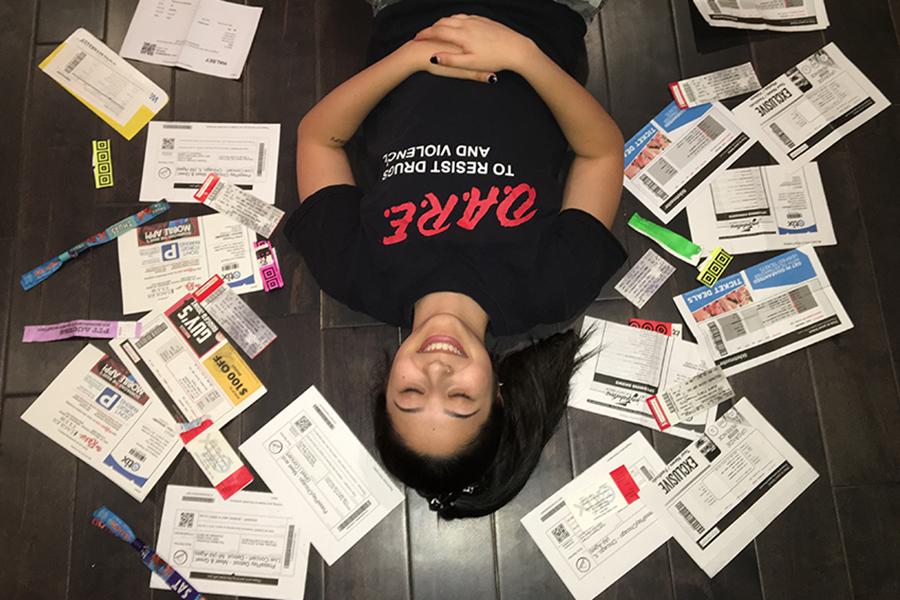 Suzy Ramirez(10) lays on her living room floor next to concert tickets. These tickets and wristbands range from Halsey to Lollapalooza.
