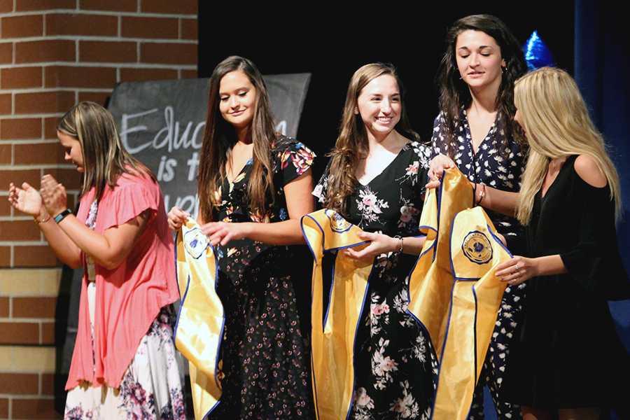  Madeline Andrews (12), Lauren Davidson (12), Courtney Carlson (12) and Megan Hraban (12) hold their graduation hoods. These girls all achieved Summa Cum Laude.
