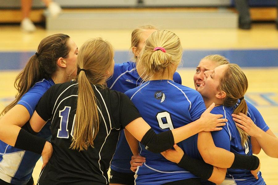 The girls congratulate each other for winning a point. The two teams were going neck and neck for that score. 