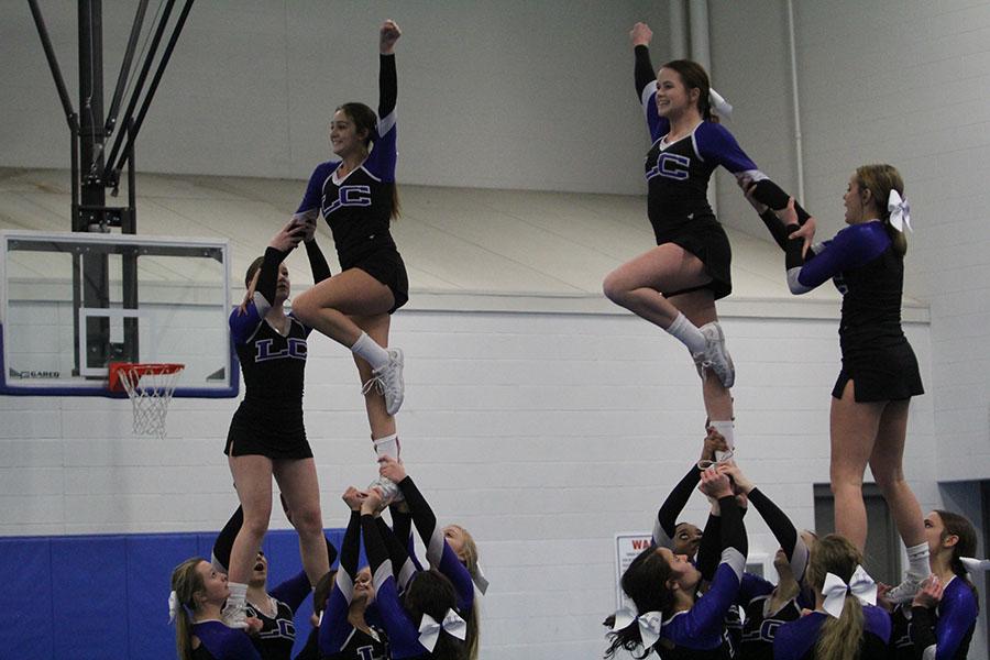 The flyers smile as their stunt groups hold them up. Cheer has traveled to Disney for the past four years. 