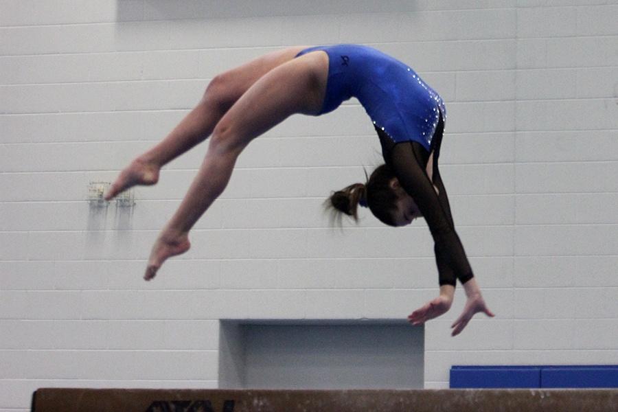 Gabbie Devries (12) does a backflip on the beam. The girls celebrated senior night after the meet.