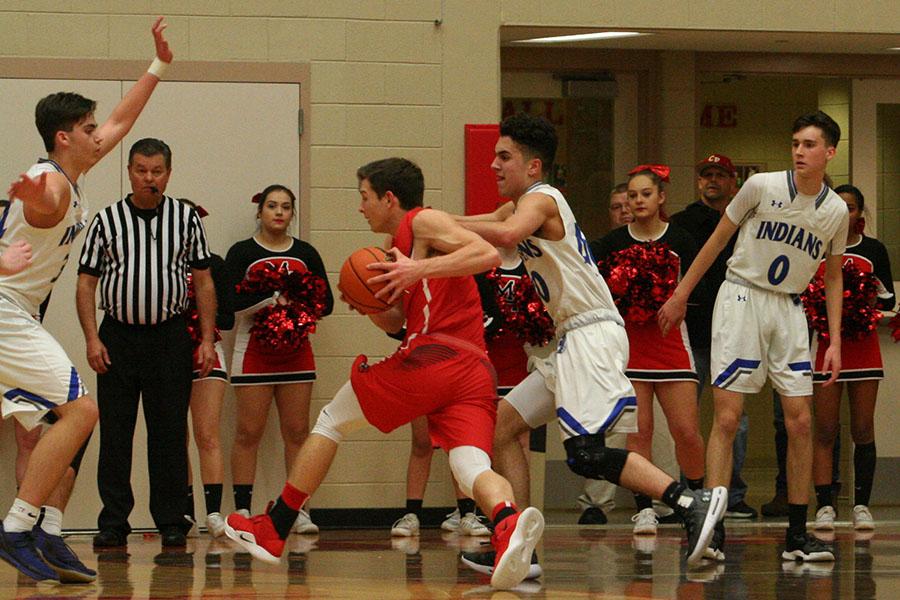  Dominic Ciapponi (12) and Kyle Blum (11) make a team effort in order to stop their opponent from making a shot and scoring. The boys, unfortunately, lost to Munster with an ending score of 57-44.  