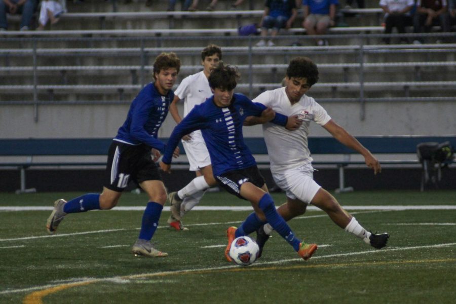 Jake Nodlin (10) takes on two opponents for the ball. He used his arm to push the opponent away. 