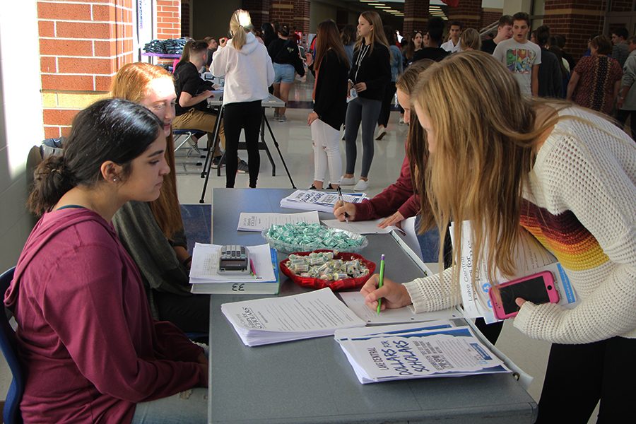 Katarina Nikolovski (12) watches students as they sign up for Dollars for Scholars. Nikolovski offered candy to the students who came and looked at the table.