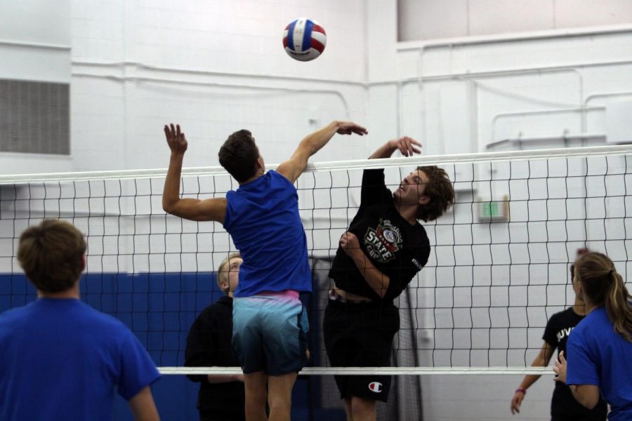 Daniel McGrath (11) and Robert MacNeill (12) go hand-in-hand to get the volleyball over to the opposing team. The two teams had a competitive match against one another.