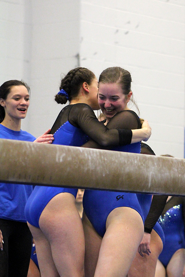 Allison Mybeck (11) rejoices after sticking the landing. Mybeck was embraced by her teammate and received applause.