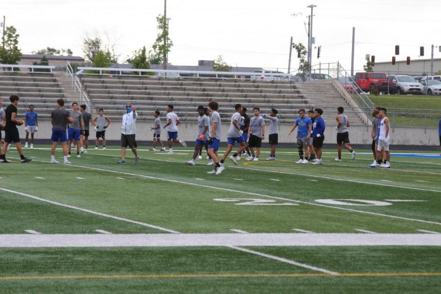 The varsity football coach wears a mask while directing the football players. One of the many changes in this school year is that coaches have to wear masks unless participating in rigorous activity. 