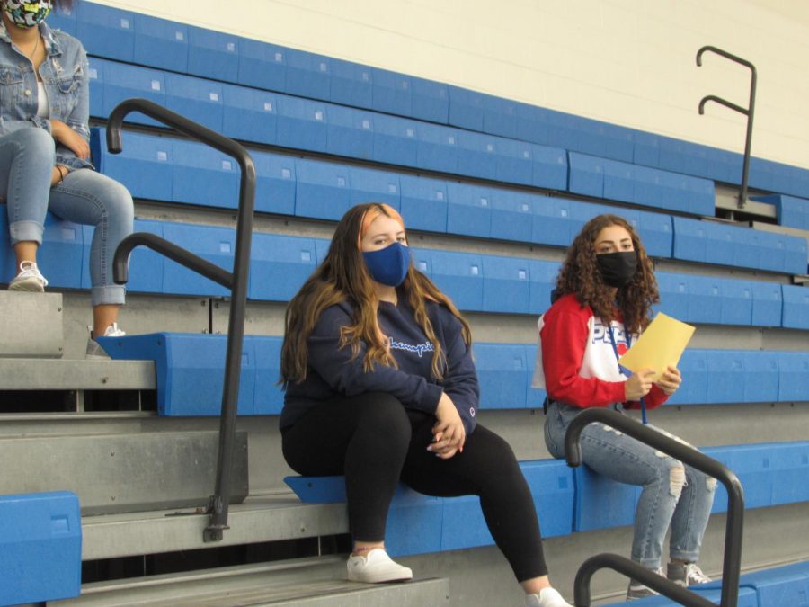 Amahlia Rodriguez (12) and Mathilda Geyer (11) listen to the coaches speak. They attended the meeting on the pool balcony to find out more information about the swimming and diving teams.