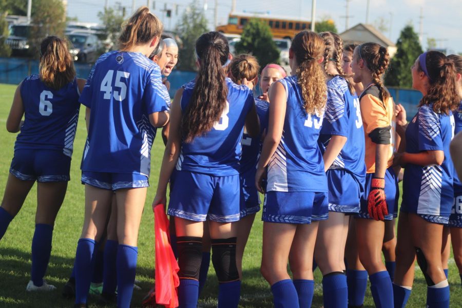 The girls huddling up right before the game starts. They were already sweating in the heat.
