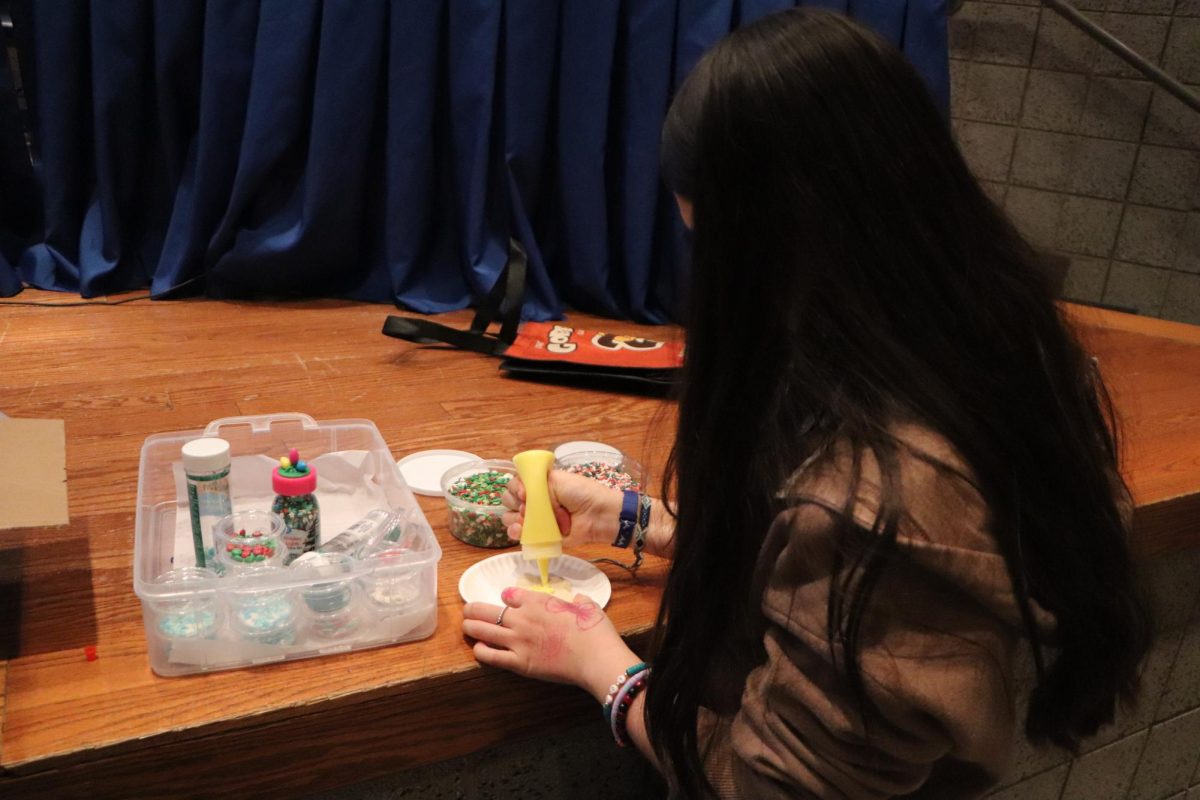 Decorating cookies, Izabella Romo (9),  picks out the color of frosting she wants. She later topped her cookie with sprinkles and other decorative items. “My favorite part of the meeting was being able to hang out with people and win prizes,” Romo said.