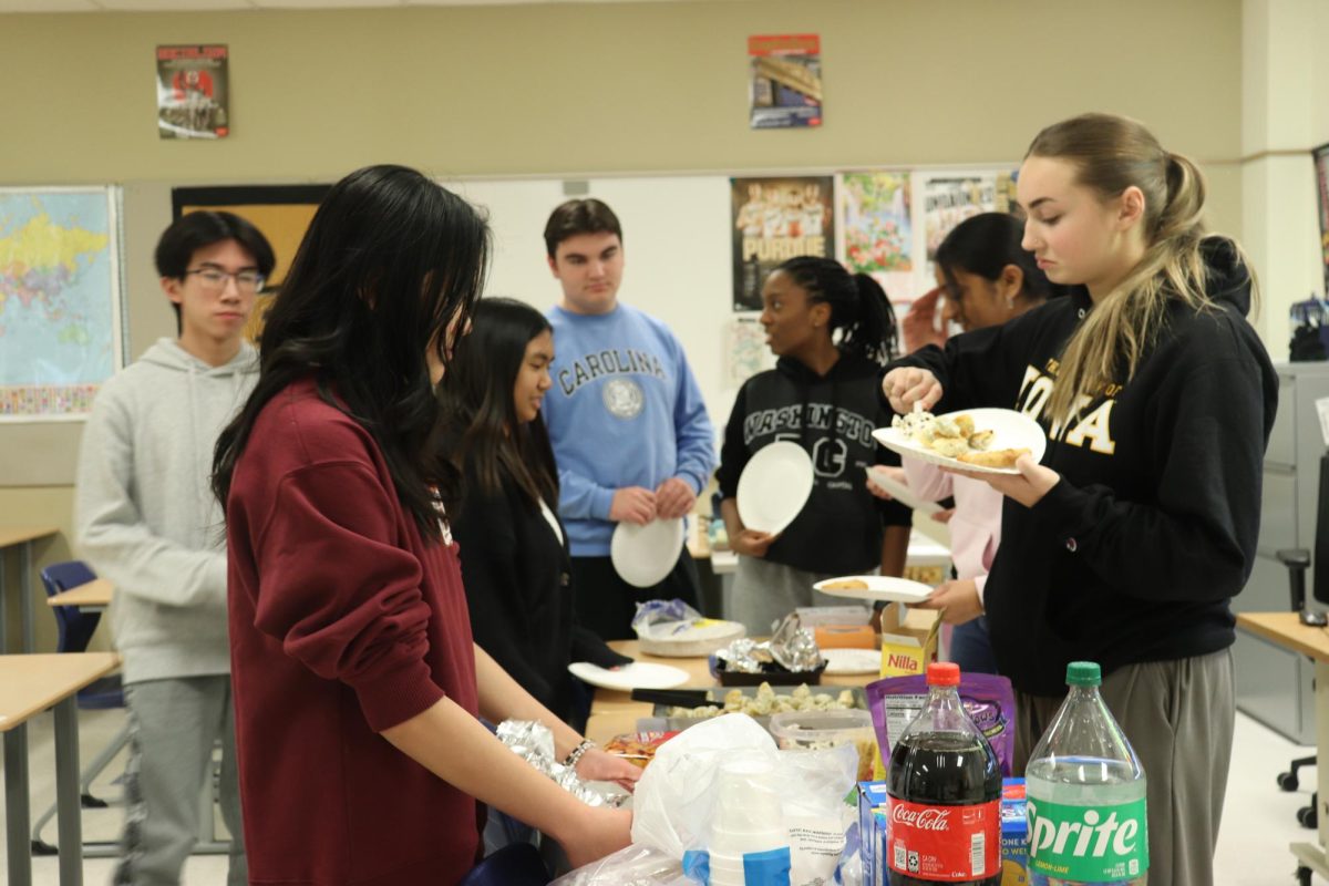 Standing around a group of desks, members of Asian American Club fill their plates with traditional Asian foods. Before the meeting started, all the members brought their dishes to Mr. Joe Bafia’s (Social Studies) classroom. “Someone brought lumpia, which is a Filipino egg roll, and Filipino crackers. I brought bibingka, which is a soft cake,” Abigail Decamotan (9) said. 